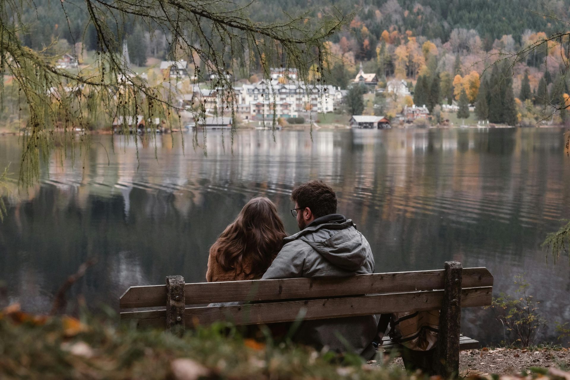 Ein romantisches Paar genießt die beschauliche Herbstlandschaft an einem malerischen Seeuferstädtchen.